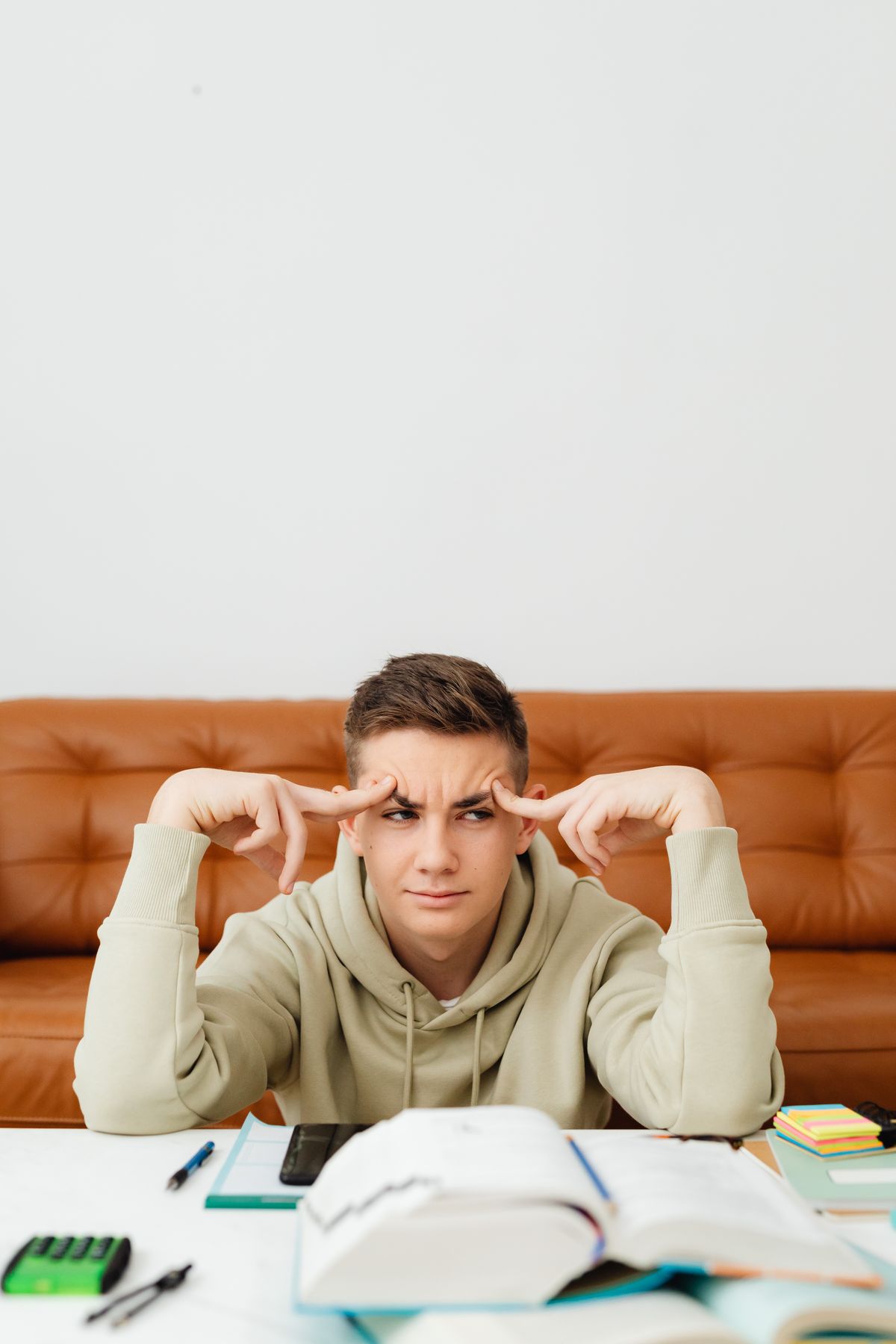 Student sitting at a desk with open textbooks looking confused