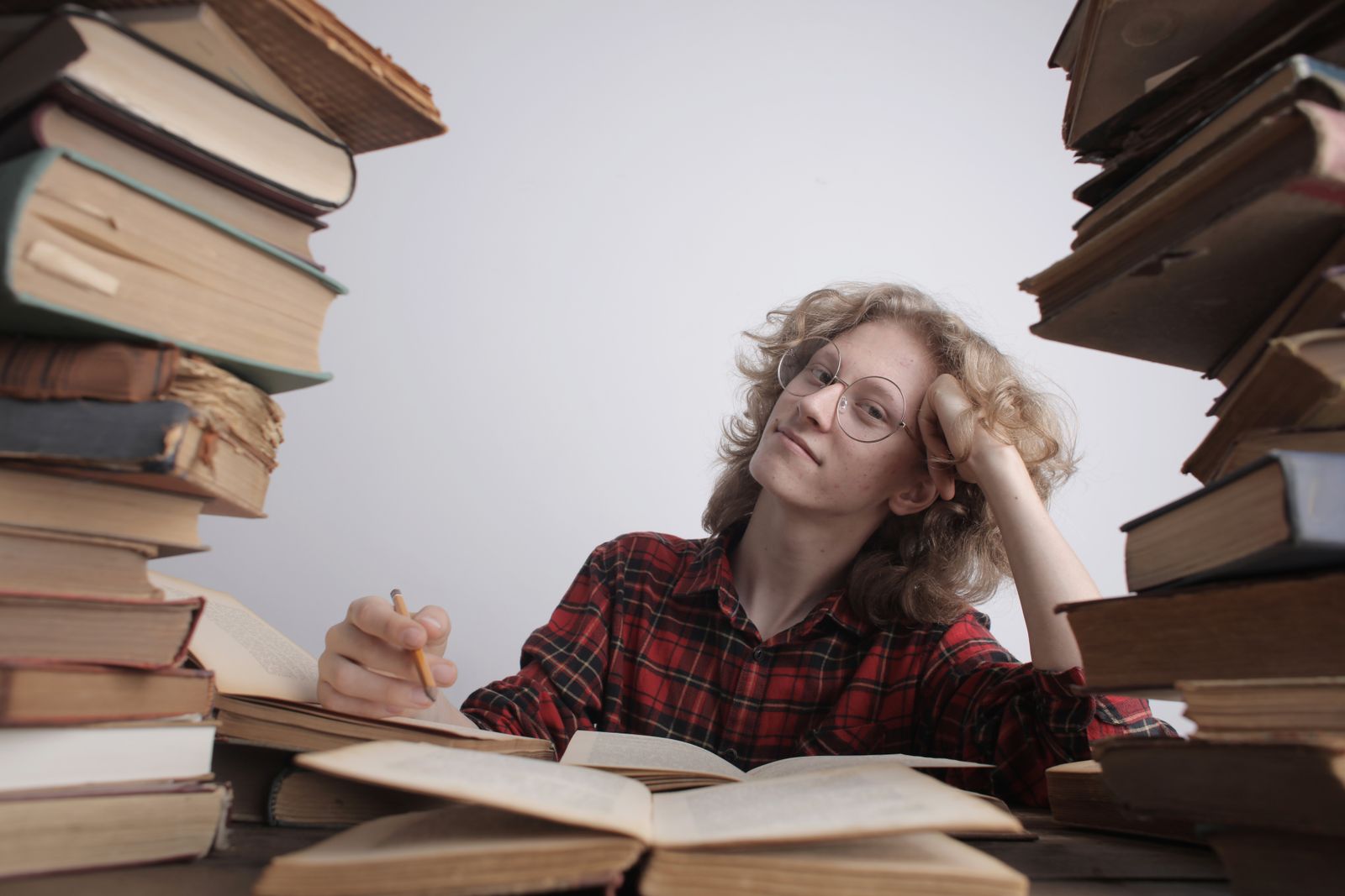 Woman surrounded by tall stacks of books looking overwhelmed