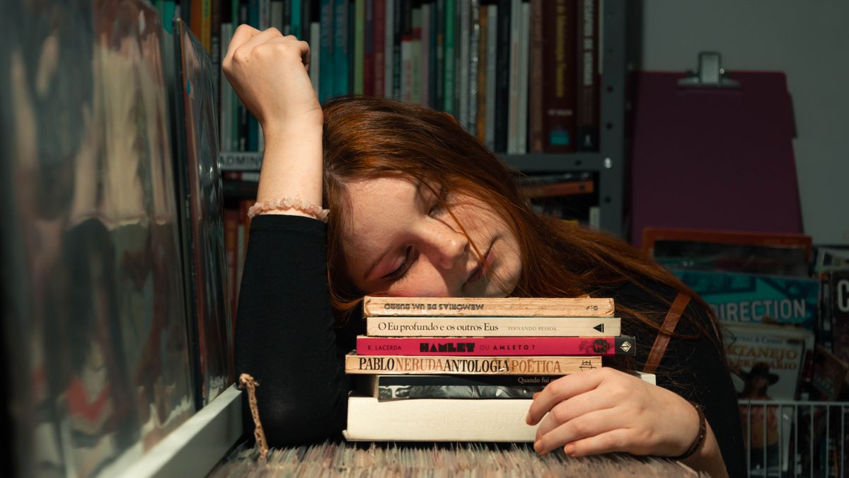 Woman resting her head on a stack of books